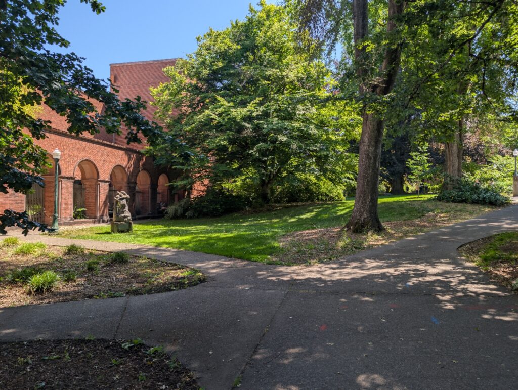 A bright, sunny day in front of the art museum on the University of Oregon campus. You see lots of greenery in front.