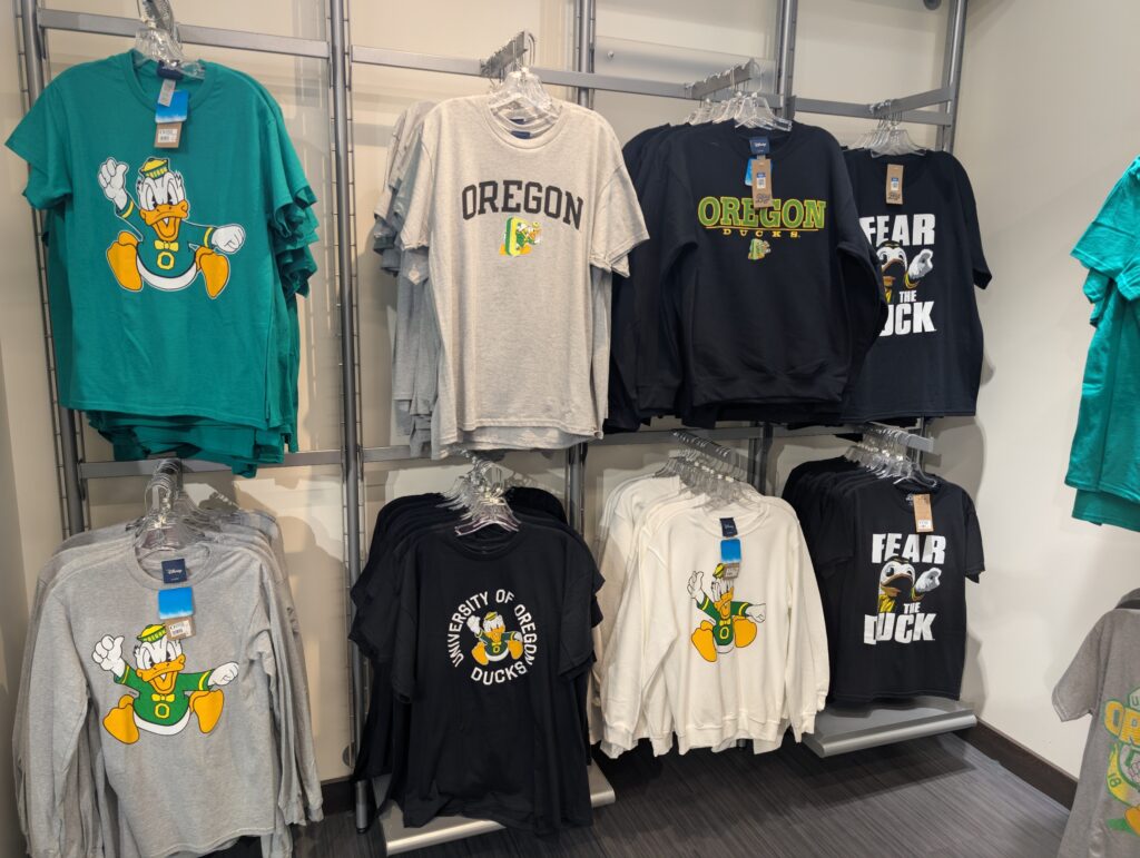 A display of T-shirts at the duck store. you see various shirts with the old duck mascot design that looks like donald duck.
