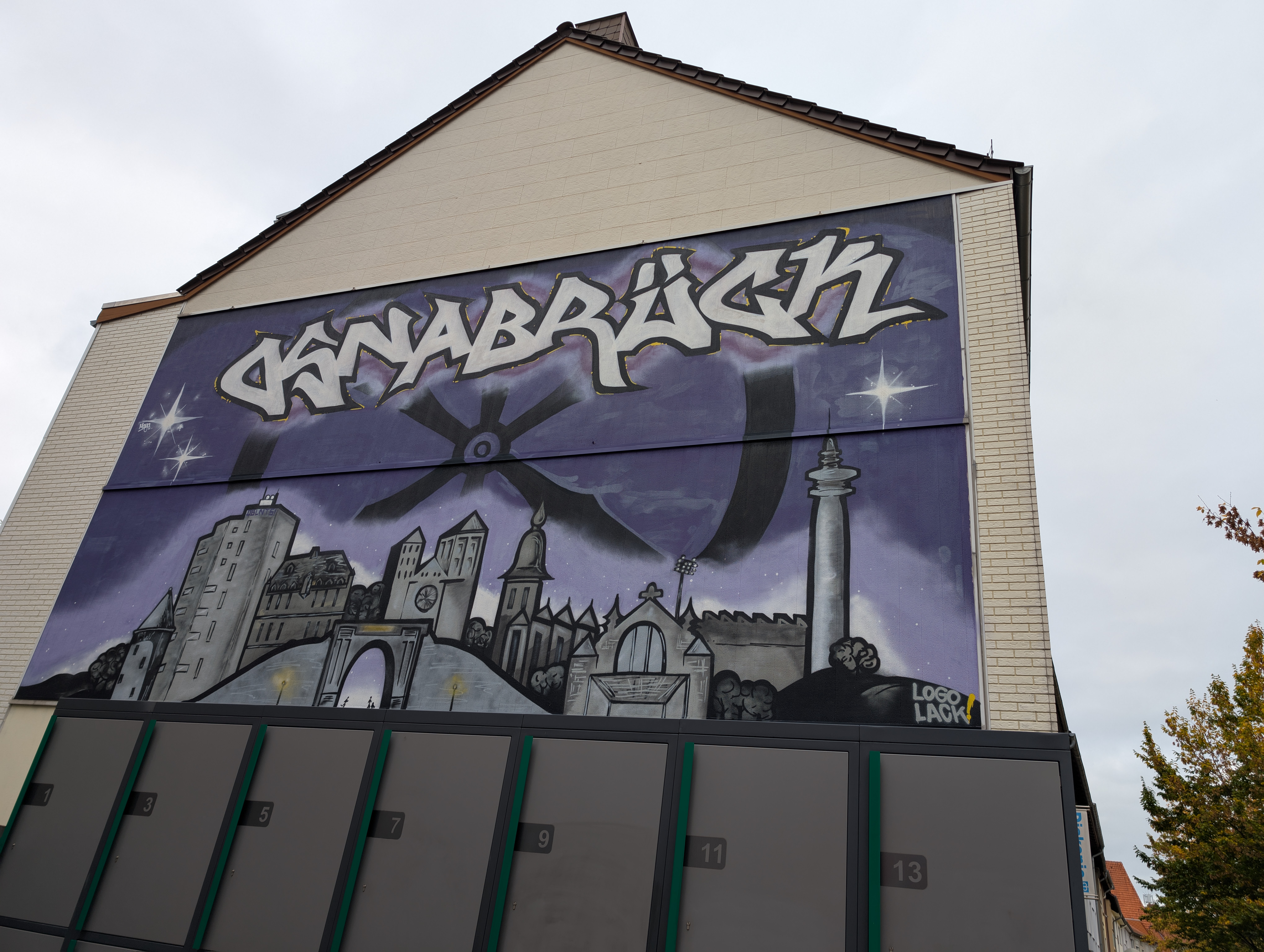 Mural of the city skyline of Osnabrück. It says Osnabrück and is on a purple background, with the town symbol of the wheel.